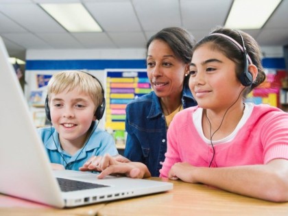 Teacher and Students looking at a laptop computer and smiling